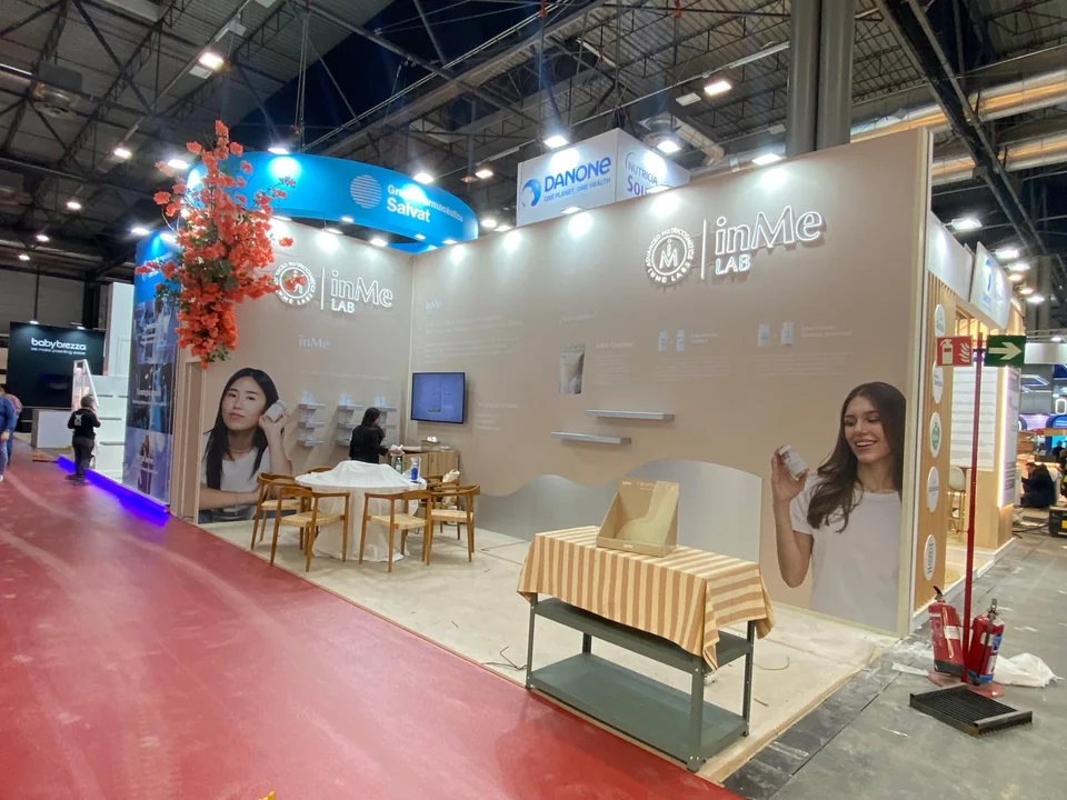Zona de conversación en un stand con iluminación suspendida y gráfica corporativa