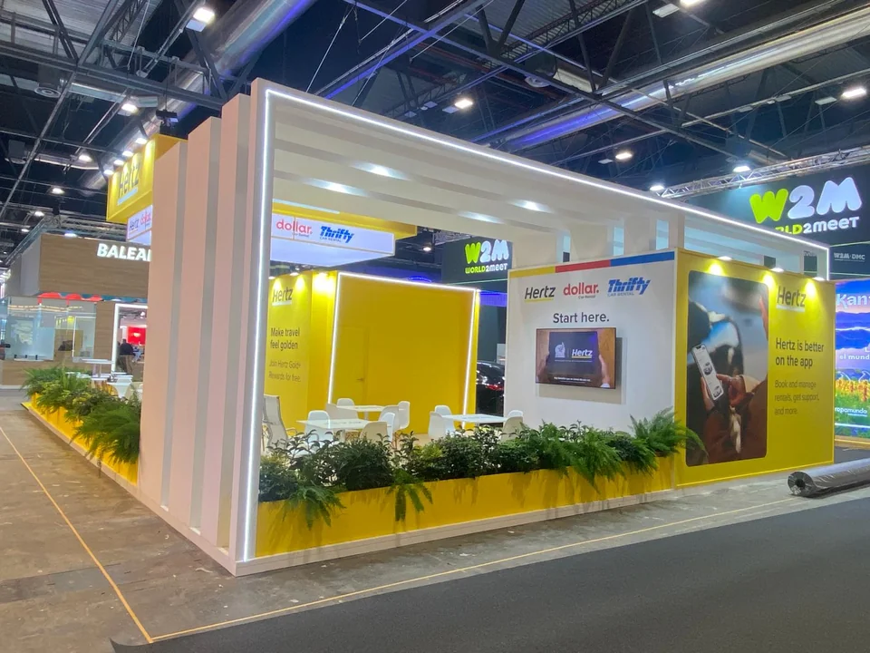 Stand blanco y amarillo con mostradores, iluminación y jardineras integradas